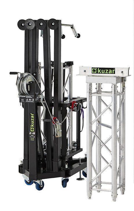 Compact folded view of the Kuzar K-10 tower lifting base on swivel wheels next to a truss section, optimized for space-saving storage and European transport.