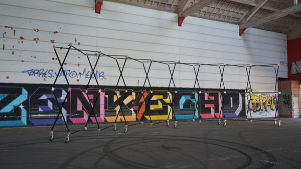 Konligo Luno Wall modular frame structure with wheels set up indoors against a graffiti wall, now available on MTN SHOP US.