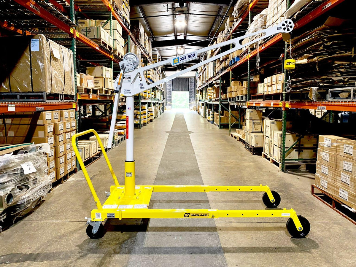 An OZ Lifting Products XR 500 Davit Crane with a white mast and boom, mounted on a yellow portable mobile wheel base inside a warehouse aisle. - imagen 3
