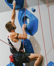 Rock climber wearing Sena EXPAND Mesh headset on indoor climbing wall - imagen 6