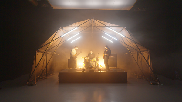 Konligo Fastival event structure with black frame and black backdrop used as a stage setup for a live band performance with dynamic lighting, now available on MTN SHOP US.