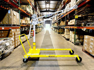 An OZ Lifting Products XR 500 Davit Crane with a white mast and boom, mounted on a yellow portable mobile wheel base inside a warehouse aisle. - imagen 3